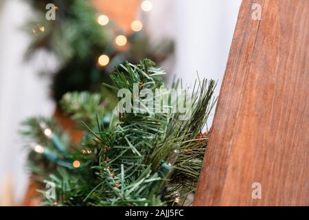 Una scala in legno è decorato con una ghirlanda di un albero di Natale e le luci. Close-up. Foto Stock