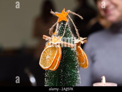 Essiccato arancione, stelle dal mandarino e cannella decorazione appeso a un albero di natale. sfondo sfocato. Foto Stock