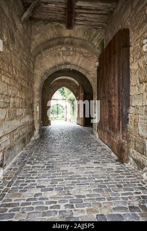 Dettaglio architettonico in pietra in questo passaggio medievale con massiccia porta di legno che conduce al bellissimo giardino parco a Rothenburg, Germania. Foto Stock