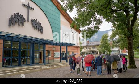 Gruppo di turisti imparare circa il famoso Passion Play, in piedi fuori il teatro in cui l'evento viene eseguito ogni dieci anni in Oberammergau Foto Stock