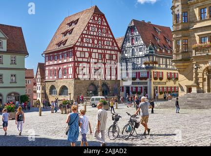 Tipica piazza mercato scena con turisti che si godono una giornata di sole nella città medievale di Rothenburg ob der Tauber, Germania, una destinazione imperdibile. Foto Stock