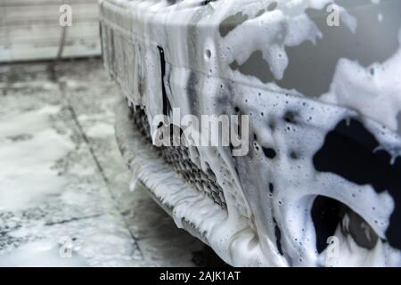 Un naso di auto coperti dalla schiuma di sapone mentre il lavaggio interno - close-up front wiew con il fuoco selettivo. Foto Stock