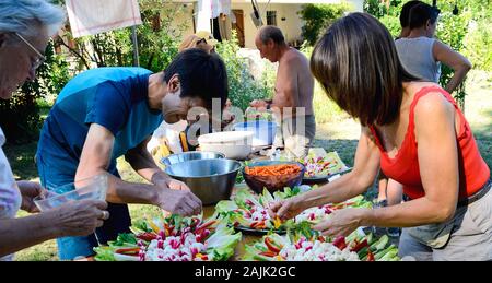 I membri della famiglia la preparazione di insalate per la celebrazione. Provenza Francia Agosto Foto Stock