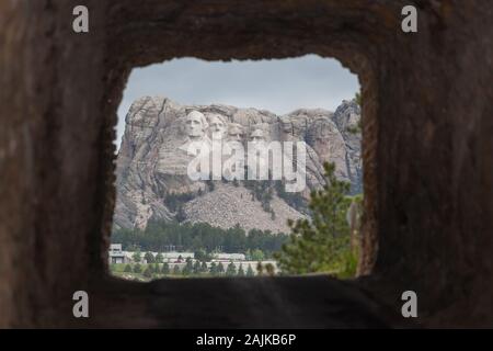 La singola corsia Doane Robinson tunnel su Iron Mountain Road con segnali di attenzione e di una vista del monte Rushmore in background. Foto Stock