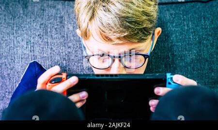 Giovani e concentrato bambino caucasico gamer con dispositivo portatile a giocare con la tecnologia giochi internet collegato con gli amici - video game addiction Foto Stock