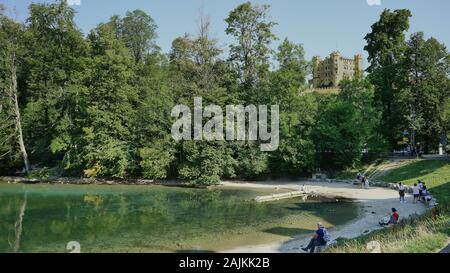 Gli amanti della spiaggia trascorrono un po' di tempo sulla sabbia lungo le rive del lago vicino al castello di Neuschwanstein di Mad King Ludwig a Hohenschwangau, in Baviera. Foto Stock