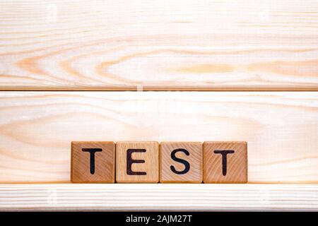 La parola di verifica fatta di legno dello sfondo. Il concetto di business. Segno di prova, esame, il concetto di apprendimento. Parola test scritto con cubetti di legno. L'istruzione di controllo di qualità. Sfondo di prova Foto Stock