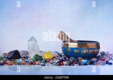 Il Tibetano Singing Bowl e multicolori guarigione pietre contro un sfondo pastello Foto Stock