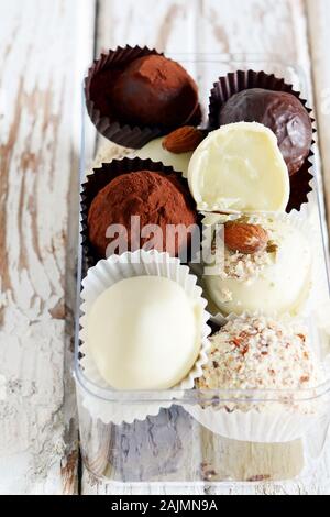 Tartufi di cioccolato in una scatola di vetro su un bianco sfondo vintage. Freschi Fatti in casa le sfere di energia. Il giorno di San Valentino, regalo di compleanno Foto Stock