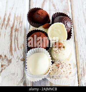 Tartufi di cioccolato in una scatola di vetro su un bianco sfondo vintage. Freschi Fatti in casa le sfere di energia. Il giorno di San Valentino, regalo di compleanno Foto Stock