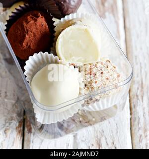 Tartufi di cioccolato in una scatola di vetro su un bianco sfondo vintage. Freschi Fatti in casa le sfere di energia. Il giorno di San Valentino, regalo di compleanno Foto Stock