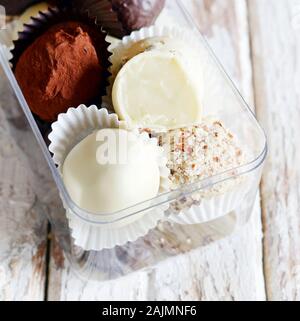 Tartufi di cioccolato in una scatola di vetro su un bianco sfondo vintage. Freschi Fatti in casa le sfere di energia. Il giorno di San Valentino, regalo di compleanno Foto Stock