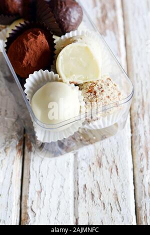 Tartufi di cioccolato in una scatola di vetro su un bianco sfondo vintage. Freschi Fatti in casa le sfere di energia. Il giorno di San Valentino, regalo di compleanno Foto Stock