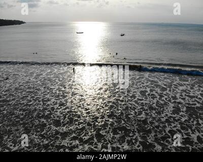 Vista aerea di surfers sul loro bordo in attesa le onde durante il tramonto, grandi onde tropicale oceano blu, drone vista del surfer cattura le onde azzurre, Bali, Indonesia Foto Stock