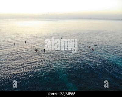 Vista aerea di surfers sul loro bordo in attesa le onde durante il tramonto, grandi onde tropicale oceano blu, drone vista del surfer cattura le onde azzurre, Bali, Indonesia Foto Stock