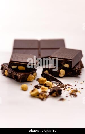 Dark pezzetti di cioccolato con nocciole intere isolati su sfondo bianco Foto Stock
