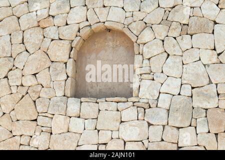 Muro di pietra a secco con arco intarsiato nella città di Cala Llonga, a Ibiza, Isole Baleari, Spagna Foto Stock