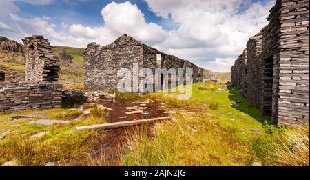 Abbandonate e ardesia edifici minerari stand in mezzo ghiaione suggerimenti e le montagne Moelwyn nella valle Cwmorthin sopra Blaenau Ffestiniog in Sn Foto Stock