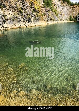 Quarry esplorato dai subacquei. Cava allagata per hobby di adrenalina. Sito subacqueo con freschi colori blu e acqua pulita con subacquei. I subacquei nella cava di blu durante l'estate. Floreffe, Belgio. Foto Stock