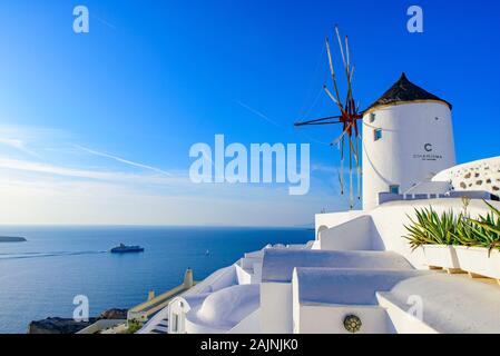 Il mulino a vento e tradizionali edifici bianco rivolto verso il Mare Egeo in Oia - Santorini, Grecia Foto Stock