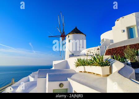 Il mulino a vento e tradizionali edifici bianco rivolto verso il Mare Egeo in Oia - Santorini, Grecia Foto Stock