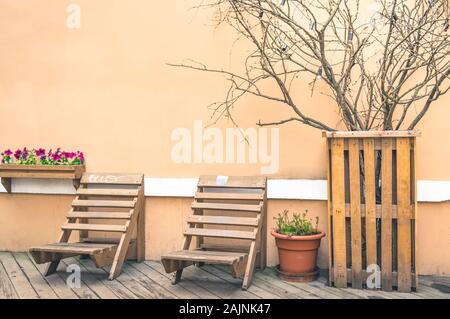 Stile Loft veranda con due sdraio in legno sul pavimento planked e slated tree con lampadine vicino a parete Foto Stock