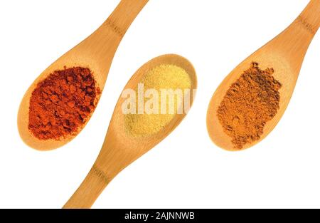 Spezie di paprika, aglio e cannella su tre cucchiai di legno isolati su uno sfondo bianco Foto Stock