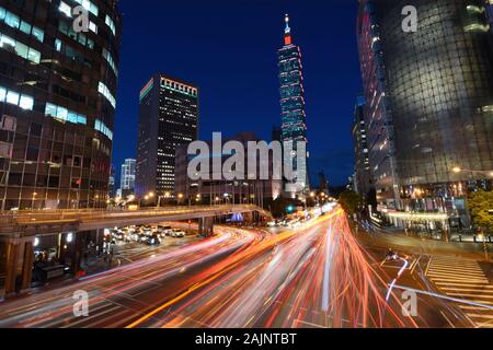 TAIPEI, Taiwan - 15 agosto 2016 - luce rossa percorsi dal veicolo striatura del traffico attraverso un incrocio occupato nella parte anteriore del Taipei 101 Foto Stock