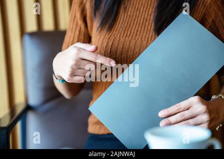 La donna è in attesa e la presentazione di una pagina vuota come modello la texture. Foto Stock