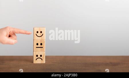Rating scala di feedback. Dito puntato eccellente servizio nominale con faccina sorridente sul blocco di legno, panorama, spazio di copia Foto Stock