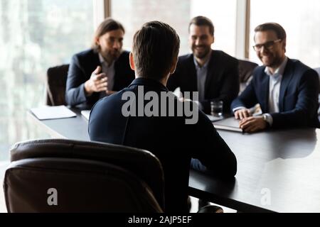 Vista posteriore del maschio candidato lavoro parlare con reclutatori Foto Stock