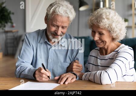 60s anziani coniugi in ufficio avvocato firmare un contratto matrimoniale Foto Stock