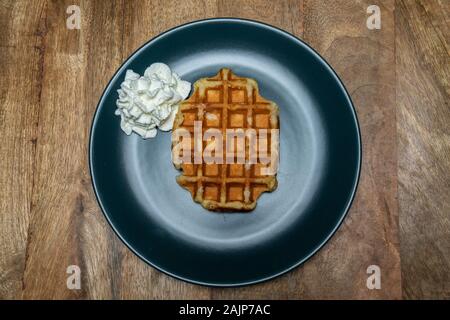 In casa i waffle belgi su una piastra. Con panna montata sul lato. Vista superiore Foto Stock