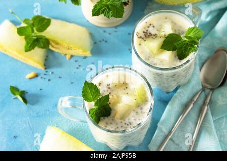 Budino di sani in un bicchiere con Chia e melone e sulla pietra blu nella tabella. Una sana prima colazione, vitamina snack, dieta e mangiare sano. Foto Stock