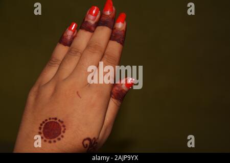 Close up della mano sinistra della ragazza con il rosso smalto per unghie e mehndi in disegni di dita e medio della mano, messa a fuoco selettiva Foto Stock