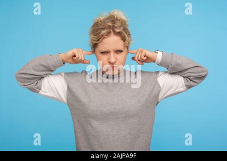 Non vogliono sentire! Irritato donna in grigio felpa sportiva che coprono le orecchie e sbuffando fuori le guance, cercando naughty e arrabbiato non ascoltate, ignorando un Foto Stock