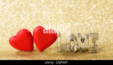 Due rossi in legno fatti a mano il cuore e la parola amore su golden luminose luci glitter sfondo bokeh di fondo Foto Stock