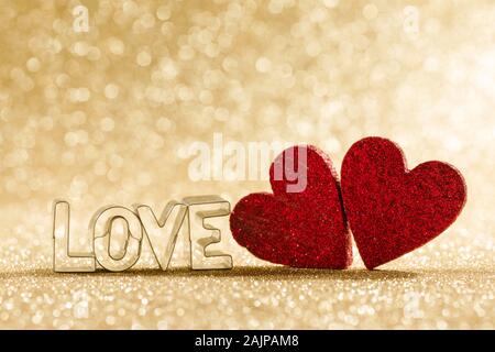 Due fatti a mano rosso glitter cuori e la parola amore su golden luminose luci glitter sfondo bokeh di fondo Foto Stock