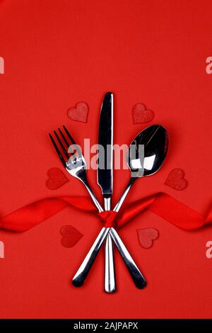 Set di posate legate con nastro di seta e cuori su sfondo rosso il giorno di San Valentino la cena concept Foto Stock