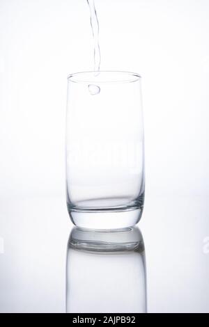 Il bicchiere di vetro è riempito con trasparente di acqua minerale. Foto Stock