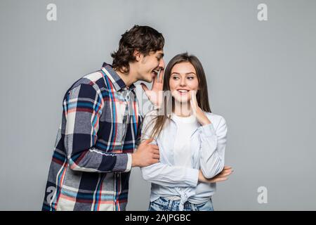 Segreto e il concetto di persone - coppia felice whispering su sfondo grigio Foto Stock