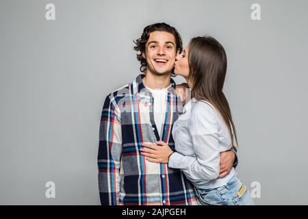 Close up ritratto di sorridente coppia giovane kissing isolato su sfondo grigio Foto Stock