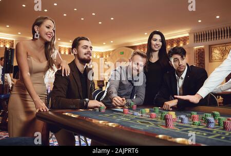 Gruppo di amici gode di vincere alla roulette poker in un casinò. Foto Stock