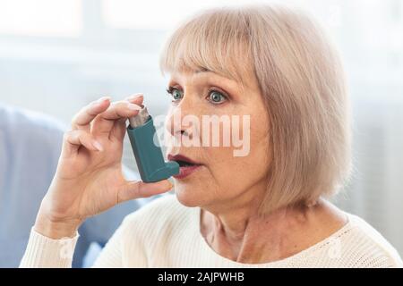 Senior donna utilizzando l'Asma Inalatore per allergie in clinica Moderna, spazio di copia Foto Stock