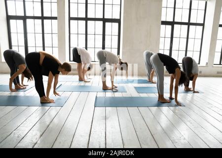 Diverse persone sportivo la pratica dello yoga, facendo piegare in avanti esercizio Foto Stock