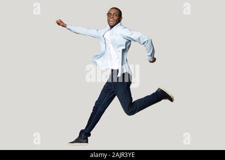 Ragazzo africano che pongono in salto isolato su grigio di sfondo per studio Foto Stock