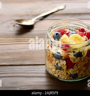 Muesli frutta in un barattolo di vetro su cucina tavolo in legno Foto Stock