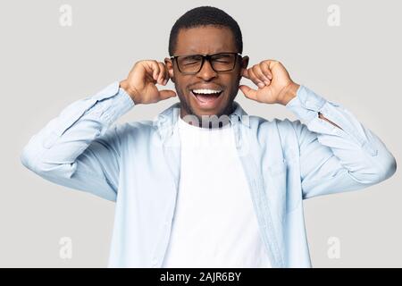 Ragazzo africano gridando collegando le sue orecchie si sente infastidito studio shot Foto Stock