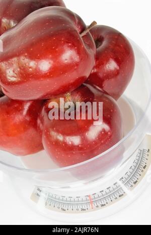 Un mucchio di grandi Red delicious pesato su una cucina peso scala di misurazione. Isolato su uno sfondo bianco. Foto Stock