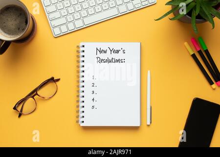 Foto di stock di 2020 anno nuovo notebook con elenco di risoluzioni e oggetti su sfondo giallo Foto Stock